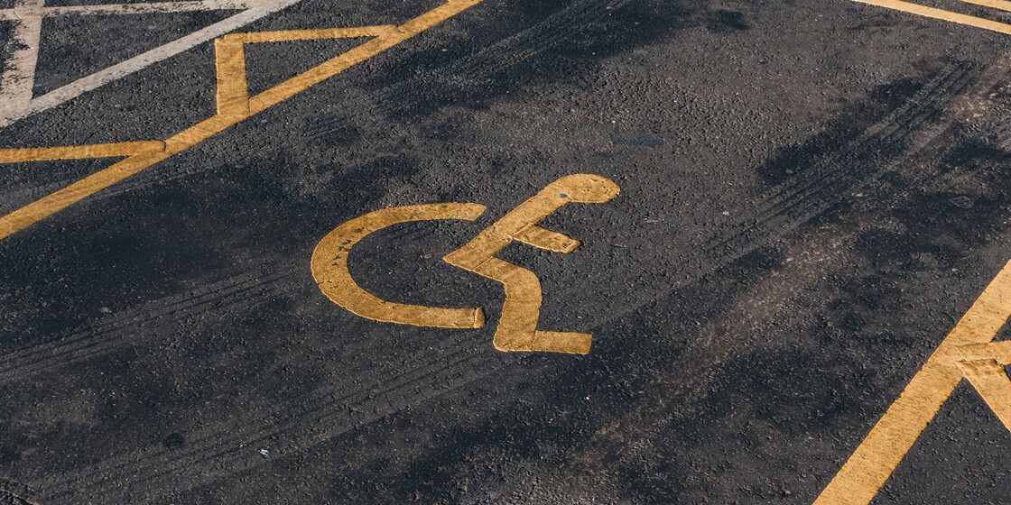 A handicap parking space with a yellow wheelchair symbol